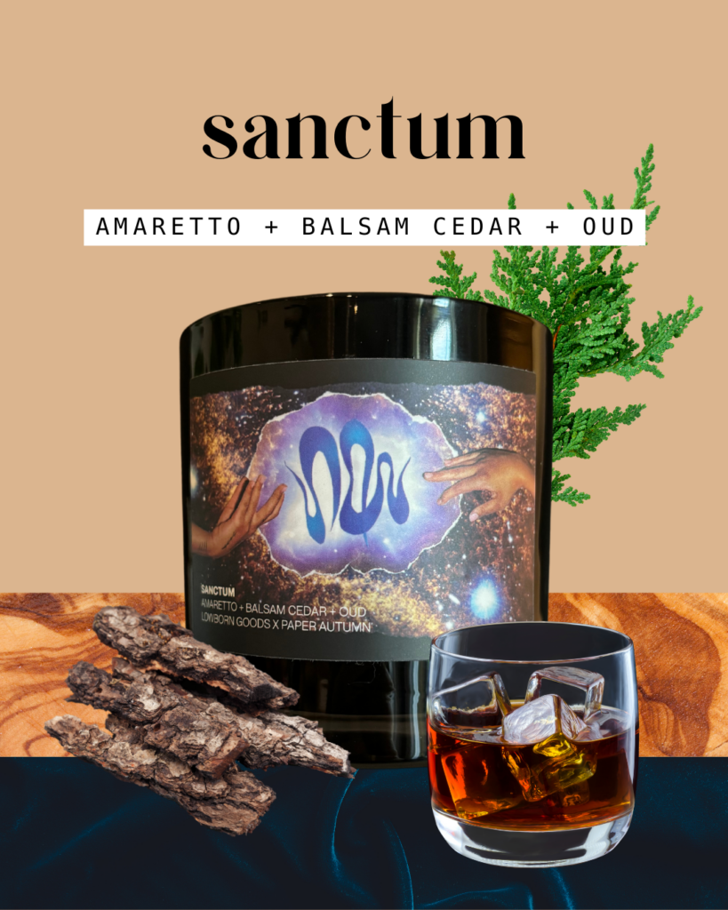 the sanctum candle is pictured in black glass featuring a label with a dynamic collage of two hands reaching out to each other over swirling designs and a background of the milky way galaxy. the candle is surrounded by cedar leaves, oud wood chips, blue velvet, and a crystal tumbler full of rum on ice. the scent notes say "amaretto + balsam cedar + oud"